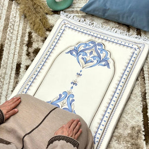 Decorative prayer mat with intricate blue patterns on a textured floor.